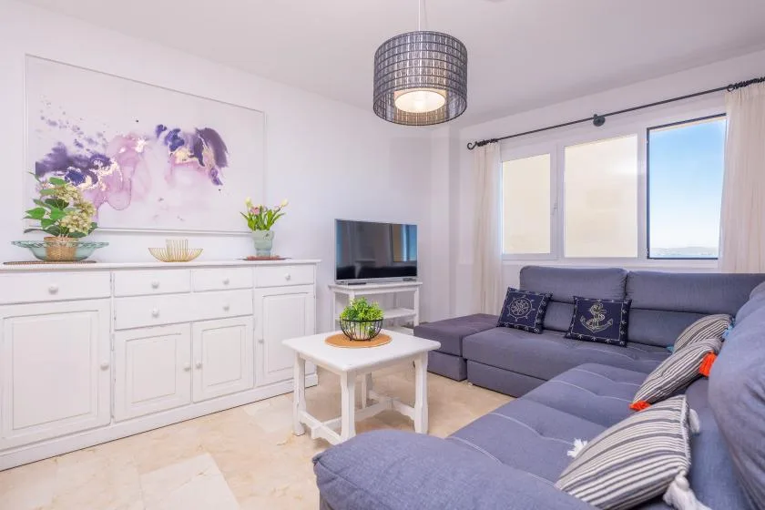 Una sala luminosa con asientos, una mesa de centro y un televisor.