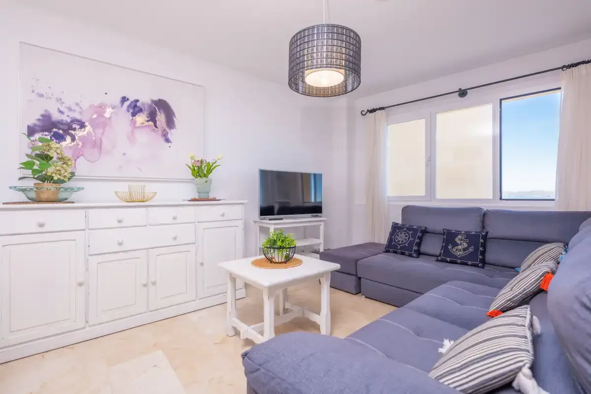 Una sala luminosa con asientos, una mesa de centro y un televisor.