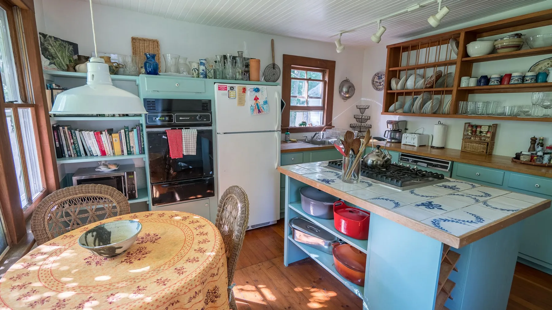 A kitchen with blue cabinets, open shelving, and a round dining table.