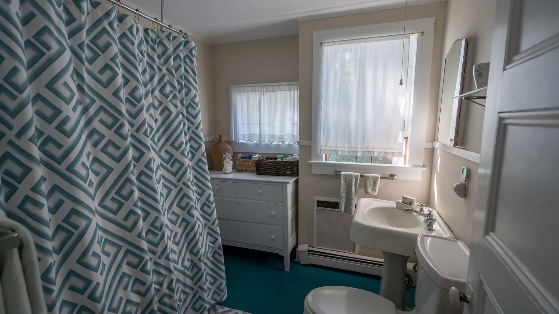 A bathroom with a patterned shower curtain, sink, and toilet.