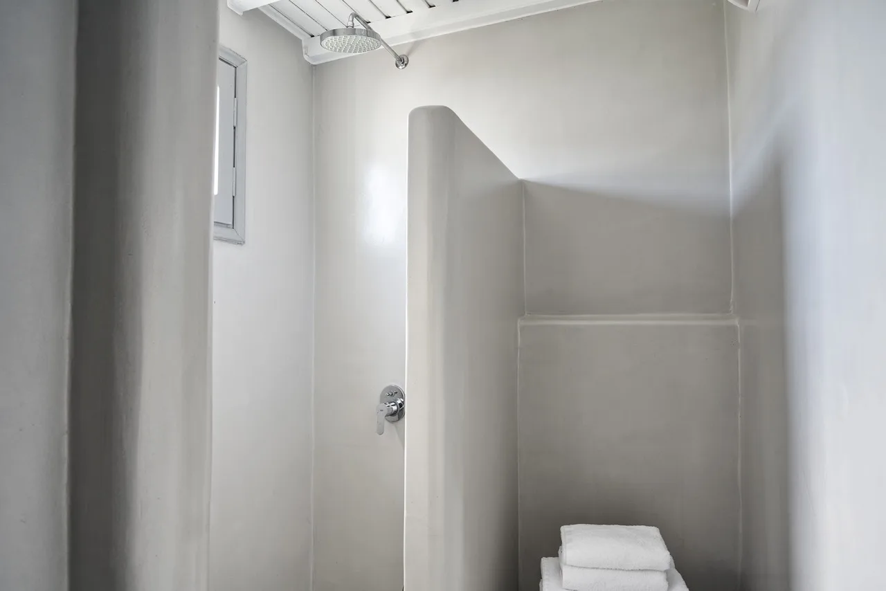 A shower area with a small window and folded towels.