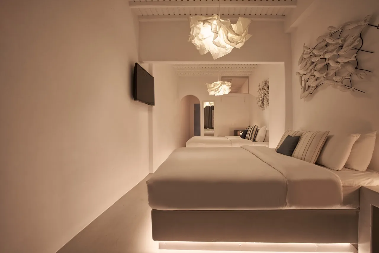 A bedroom with beds, pillows, and a wall-mounted television.