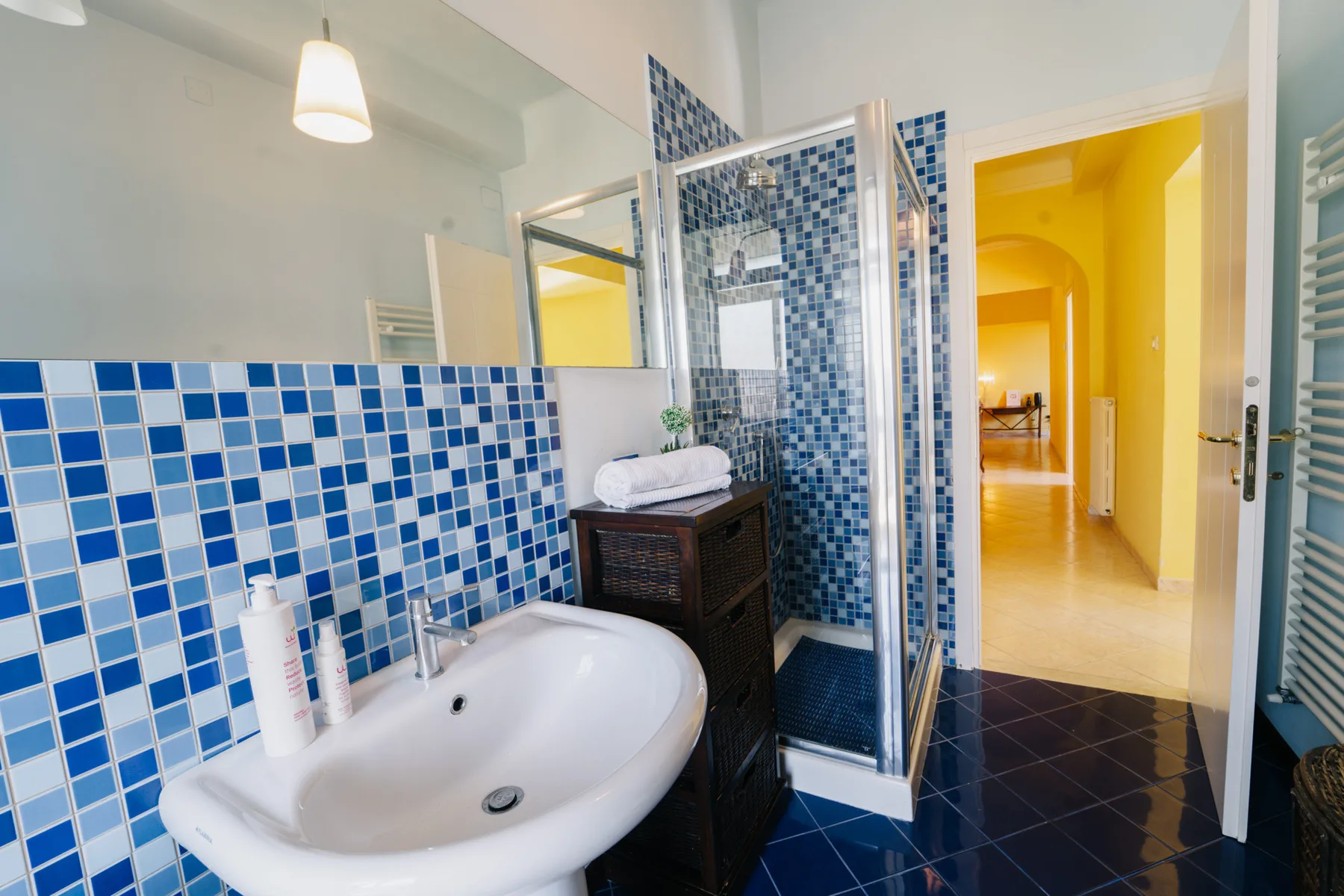 A bathroom with a white sink, blue tiled walls, and a glass shower.