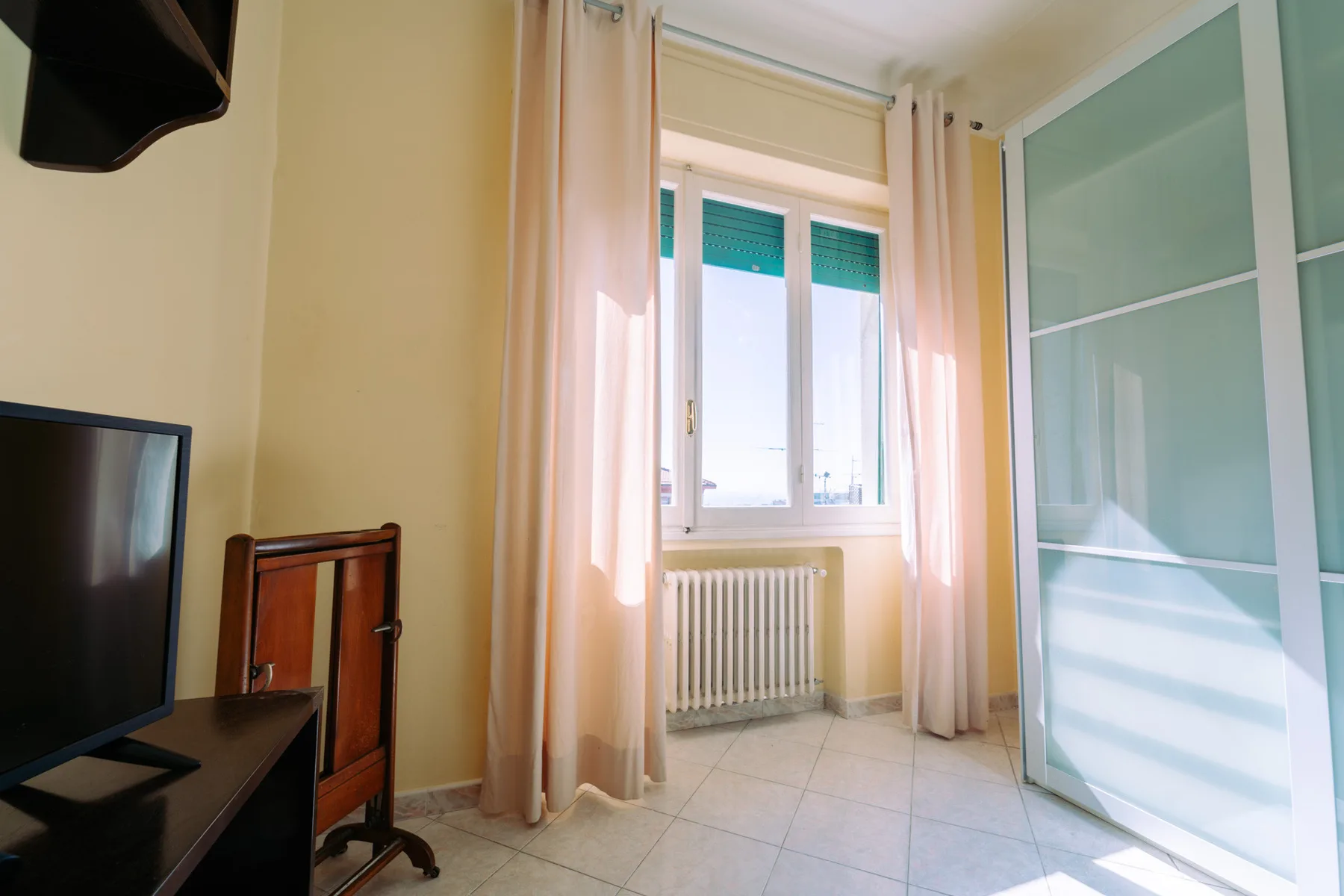 A bright room with a window, curtains, and a radiator.
