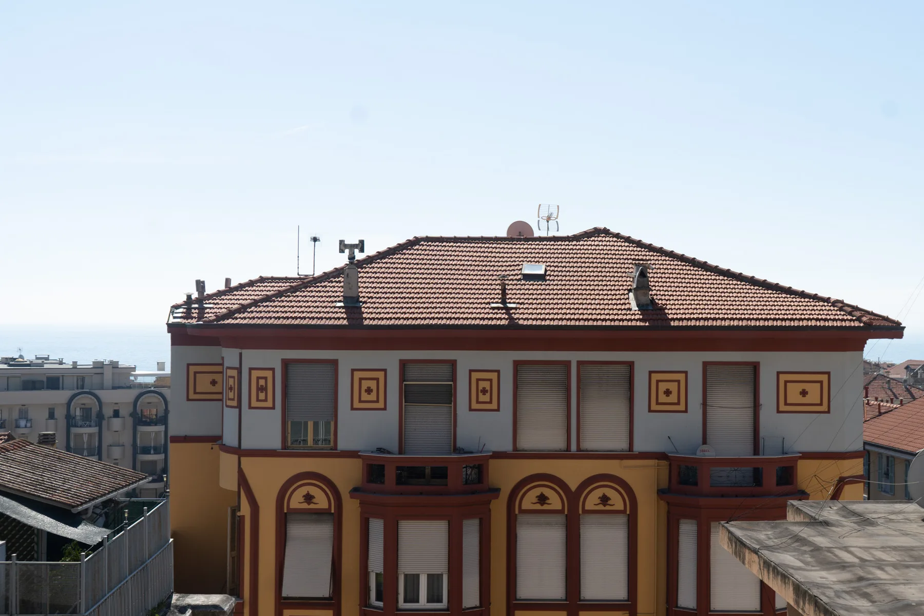 A multi-story building with a red tiled roof and rows of windows.