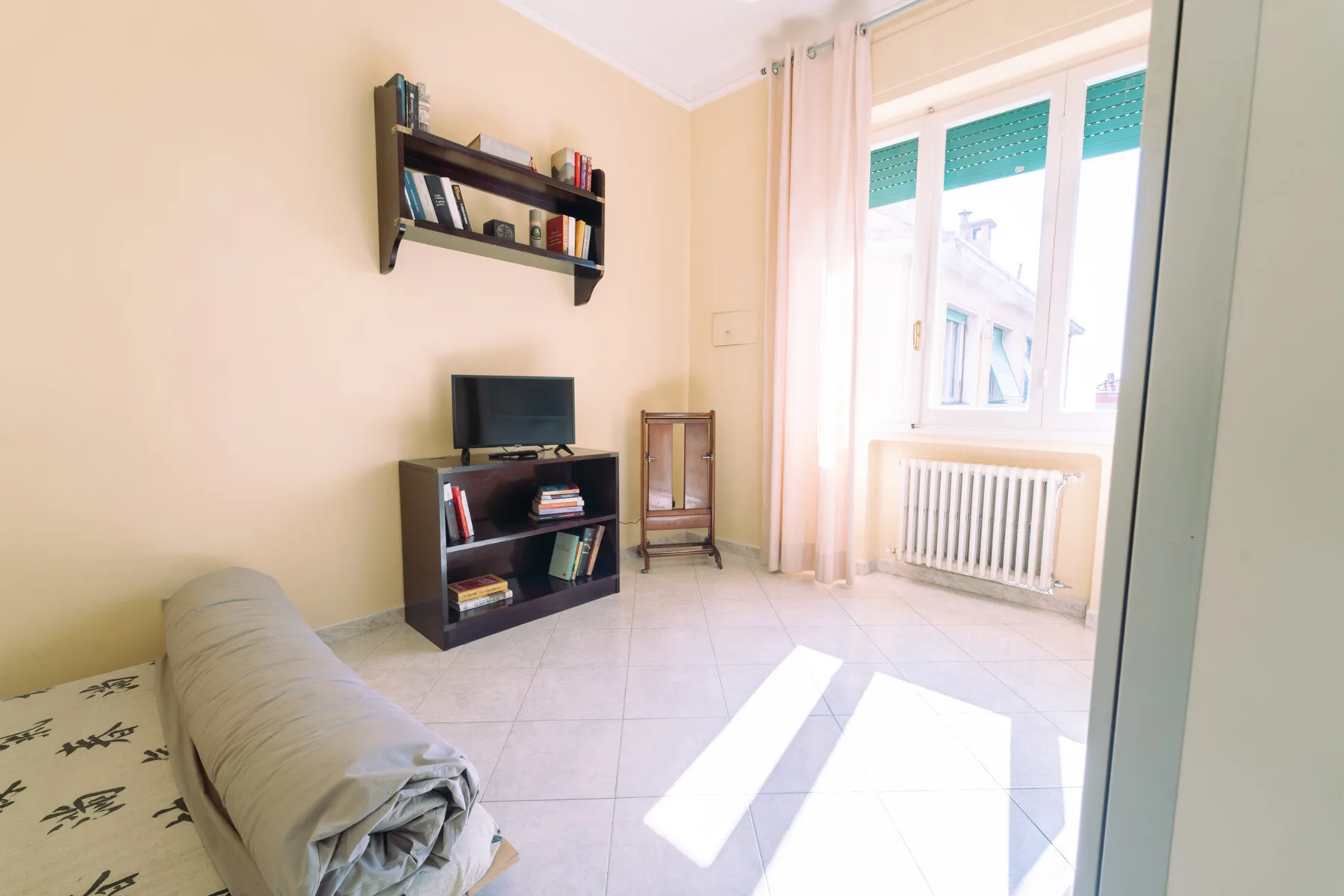 A living room with a television and seating beside a bright window.