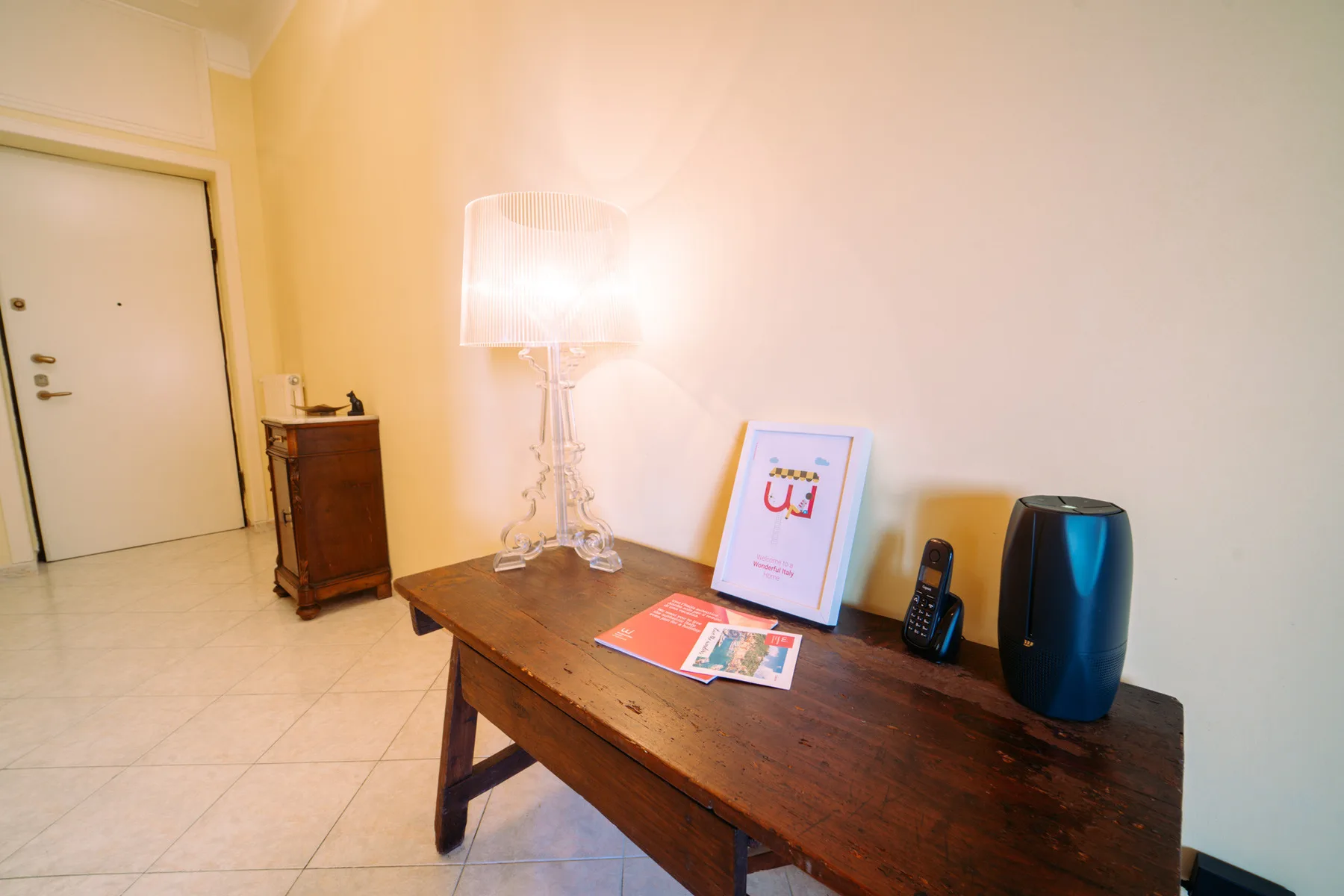 A warmly lit entry area with a wooden console table and lamp.