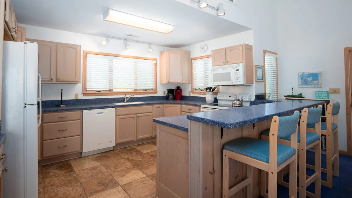 Una cocina con gabinetes de madera, una isla central y asientos de barra.
