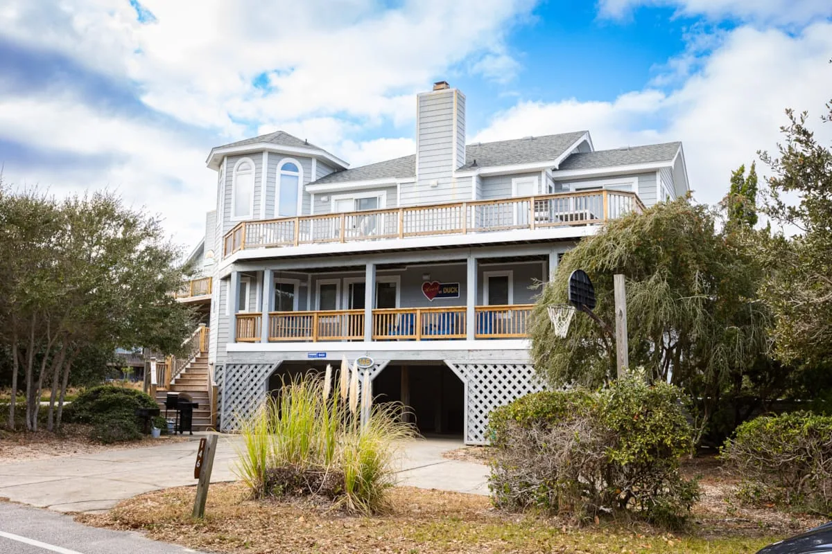 A large coastal-style house with broad porches and landscaped shrubs.