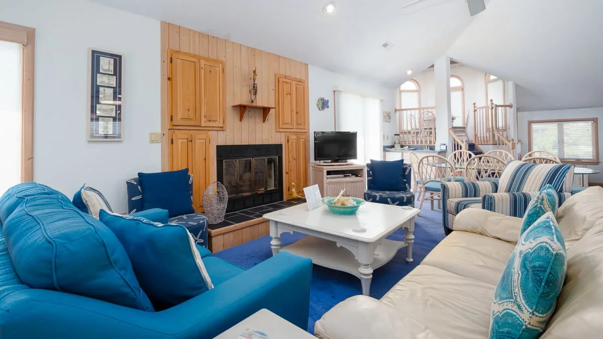 A spacious living room with blue and cream seating around a white coffee table.
