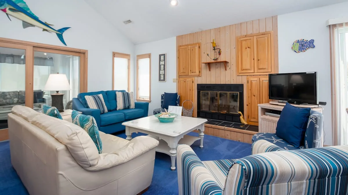 A living room with seating arranged around a fireplace and television.