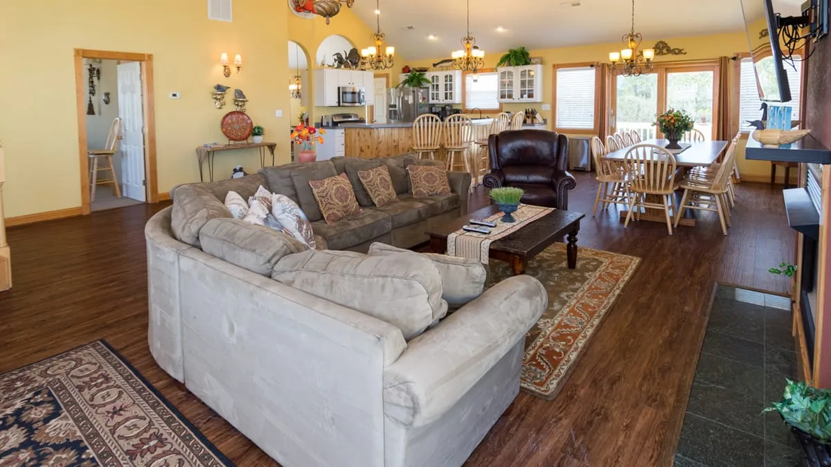 A living and dining area with a sectional sofa, dining table, and large windows.