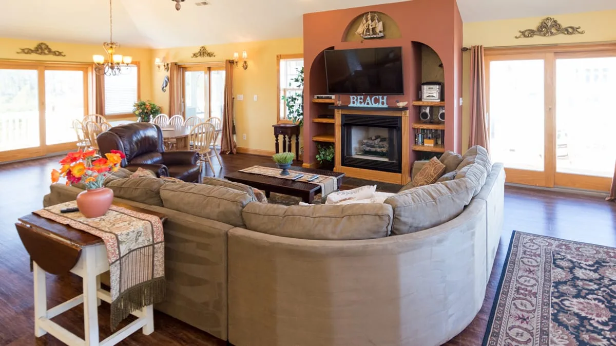 A bright living room with curved seating, a fireplace, and large windows.