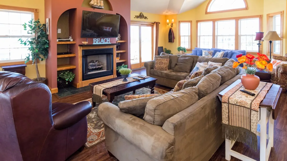 A bright living room with ample seating, a fireplace, and large windows.