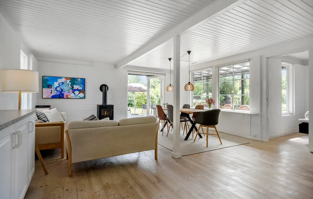 An open-plan living and dining area has seating, a table, and large windows.