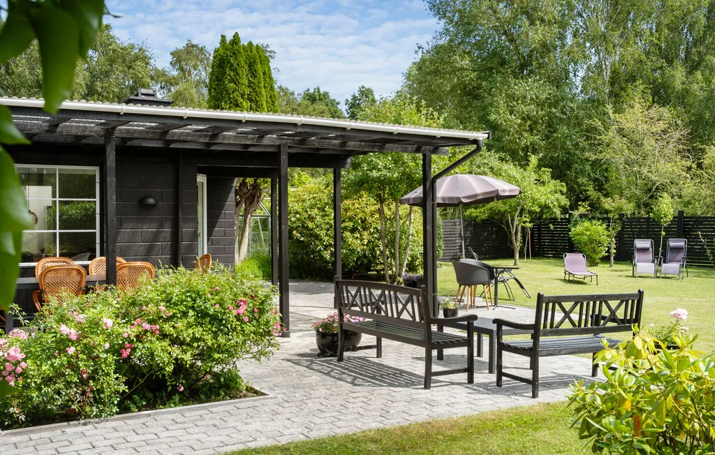 A garden patio with outdoor seating beneath a wooden pergola.