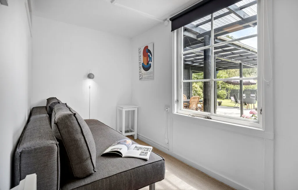 A bright sitting area with gray seating beside a large window overlooking a garden.
