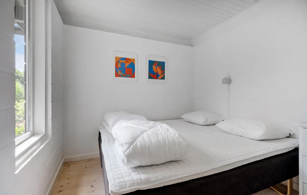 A bright bedroom with a large bed, white bedding, and colorful wall art.