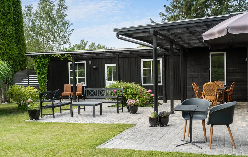 An outdoor patio with seating beside a dark house and a grassy yard.