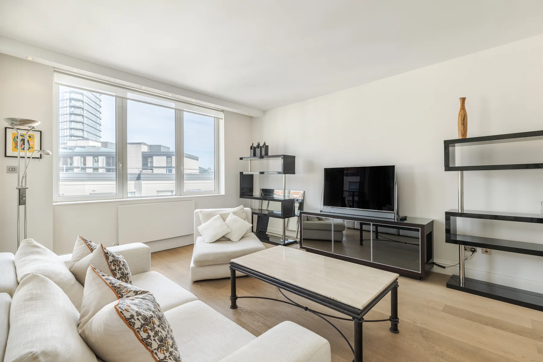 A bright living room with seating, a television, and large windows.