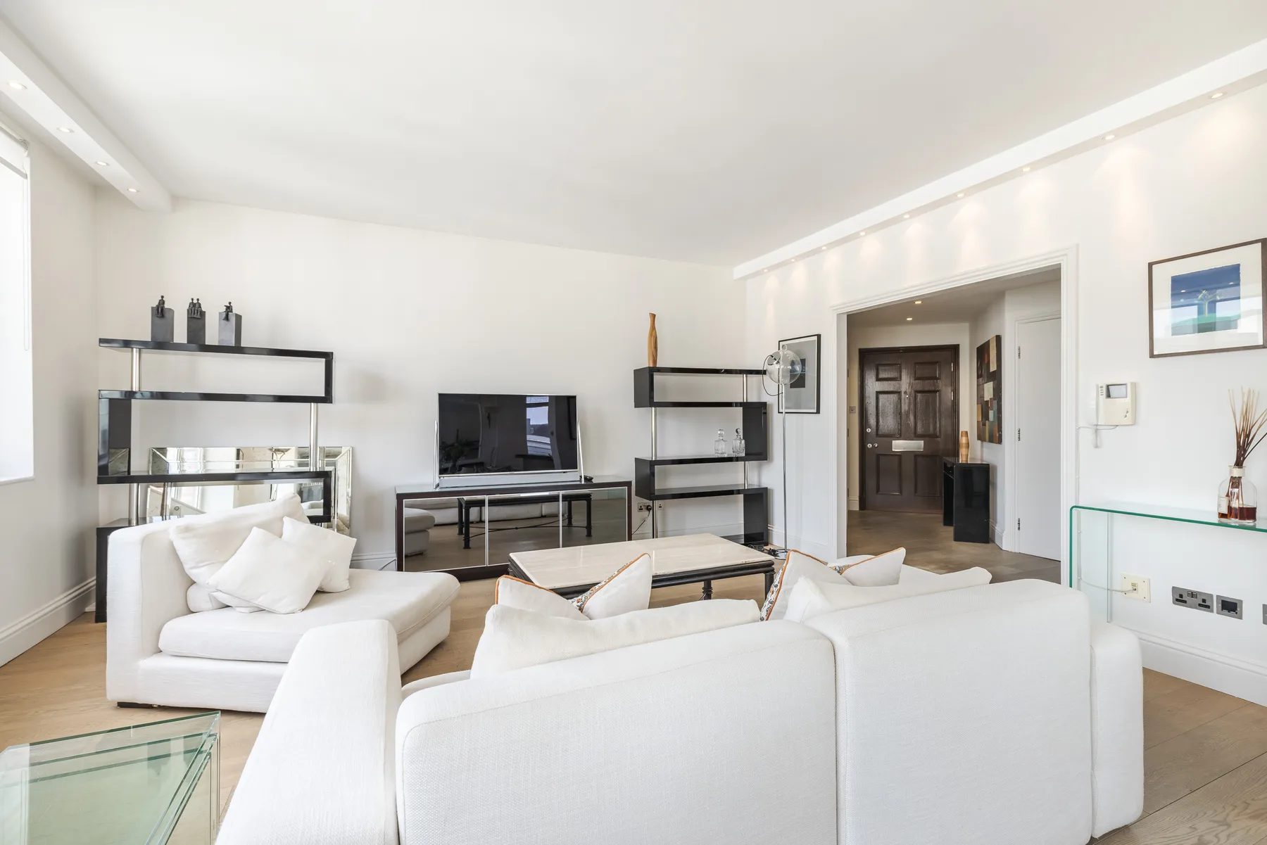 A bright living room with white seating arranged around a television and coffee table.