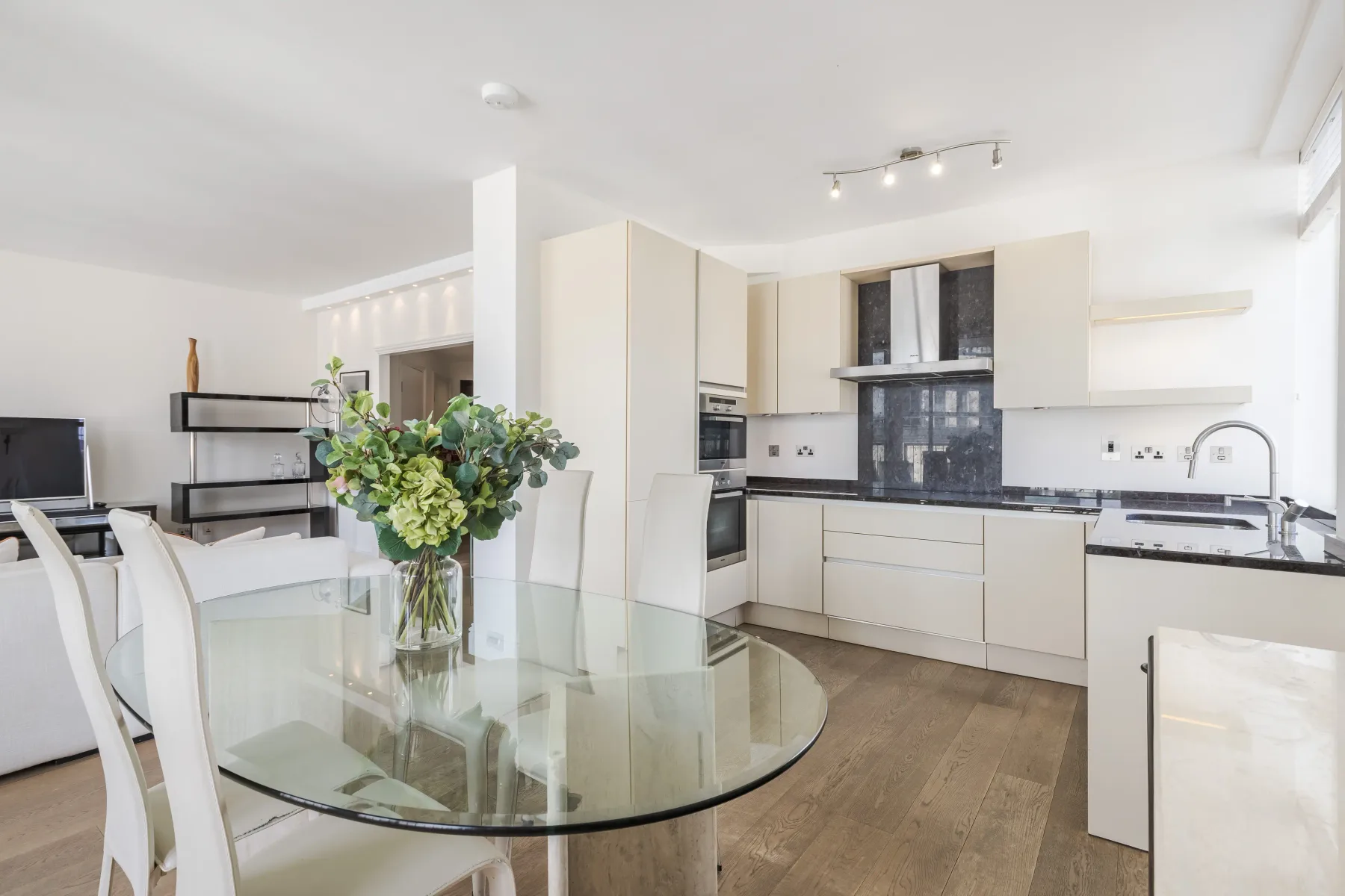 A bright open-plan kitchen and dining area with a glass dining table.