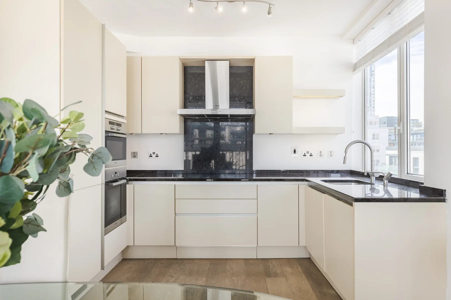 A bright modern kitchen with white cabinets and dark countertops.