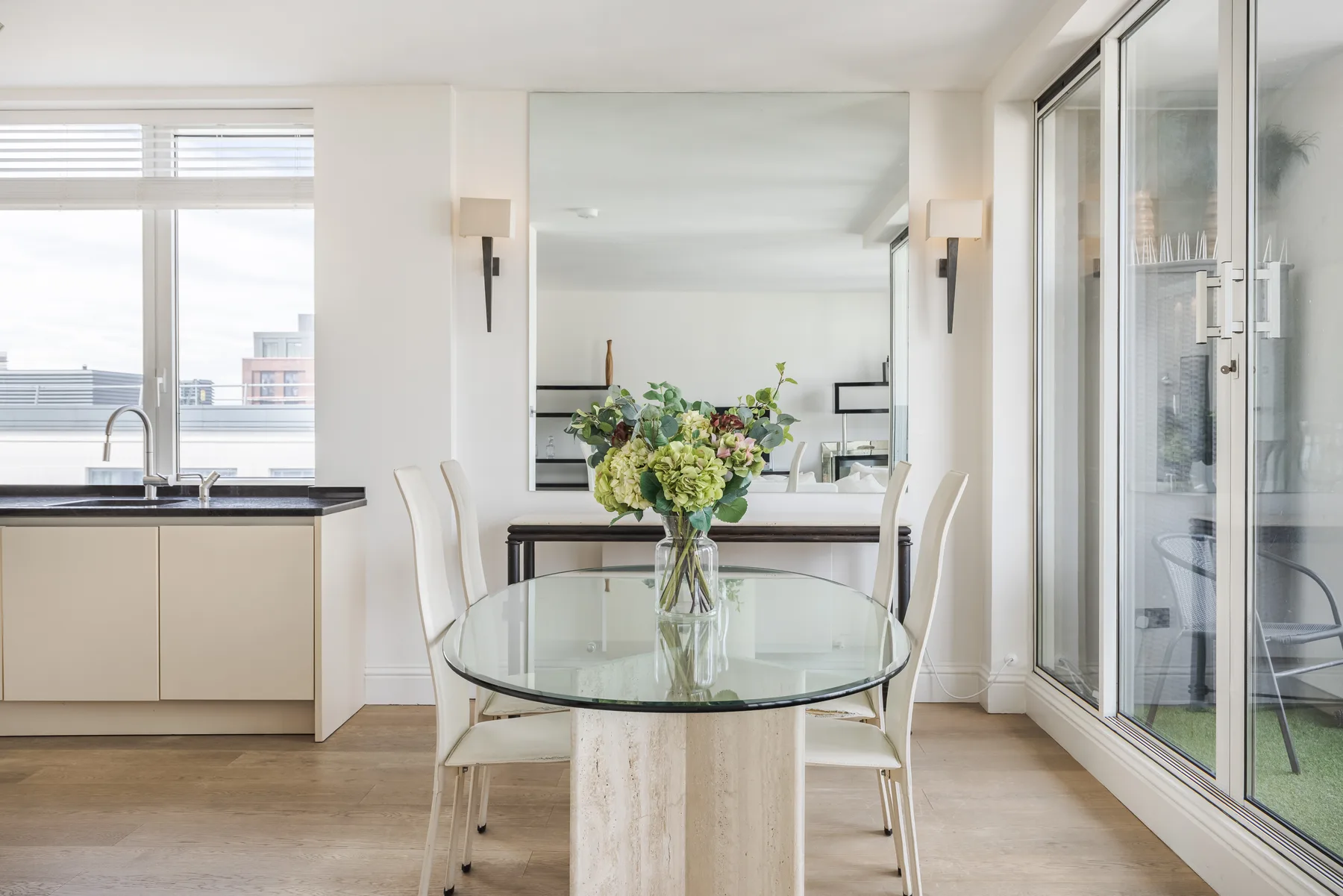 A bright dining area with a glass table and large windows.