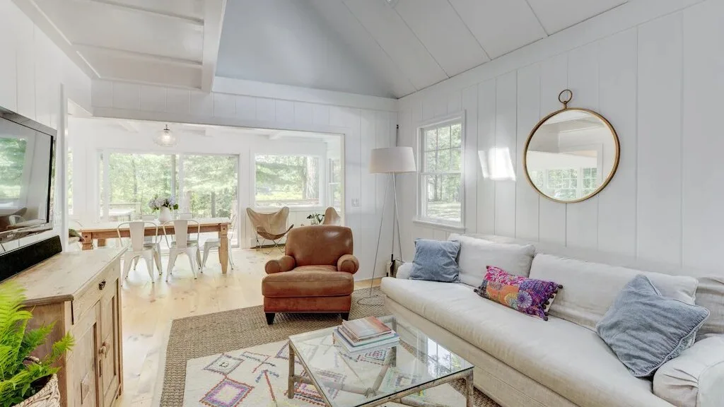 Una sala luminosa con un sofá blanco y una mesa de centro de vidrio.