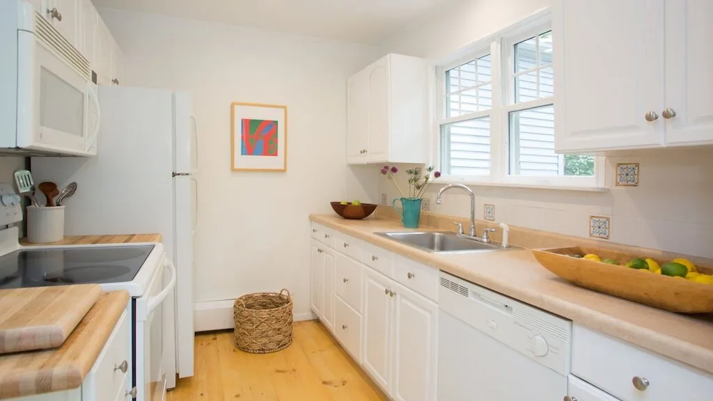 Una cocina luminosa con gabinetes blancos, un fregadero y una ventana.