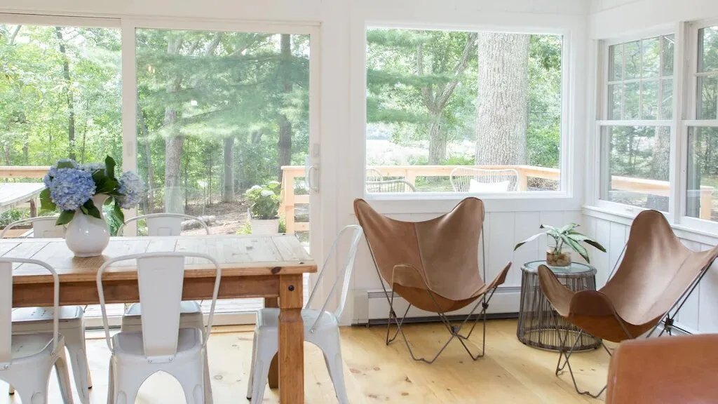A bright dining and sitting area with large windows overlooking greenery.