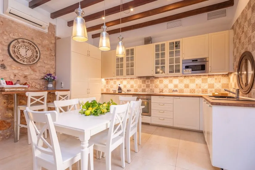 A bright kitchen and dining area with white cabinets and a set table.