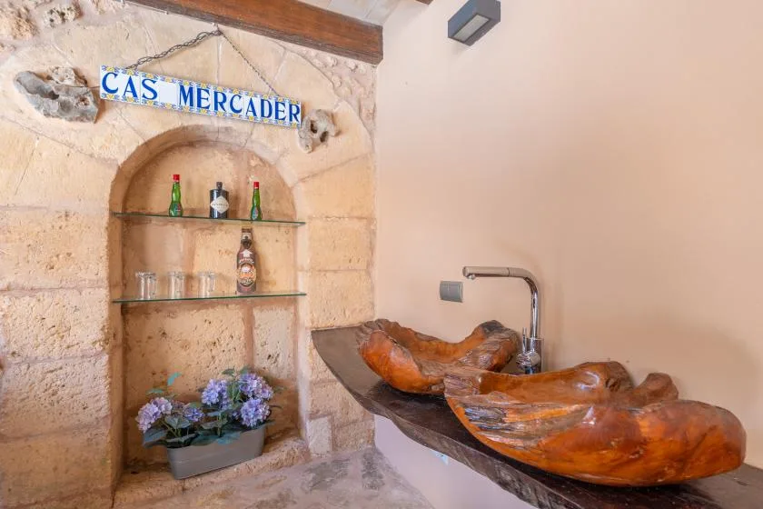 A stone bathroom vanity has two carved wooden basins and a recessed wall shelf.