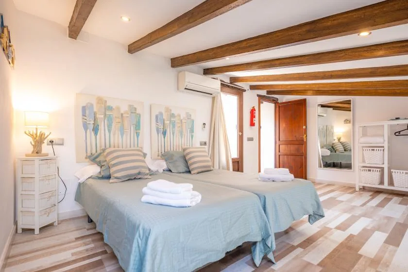 A bright bedroom with a bed dressed in pale blue bedding and striped pillows.