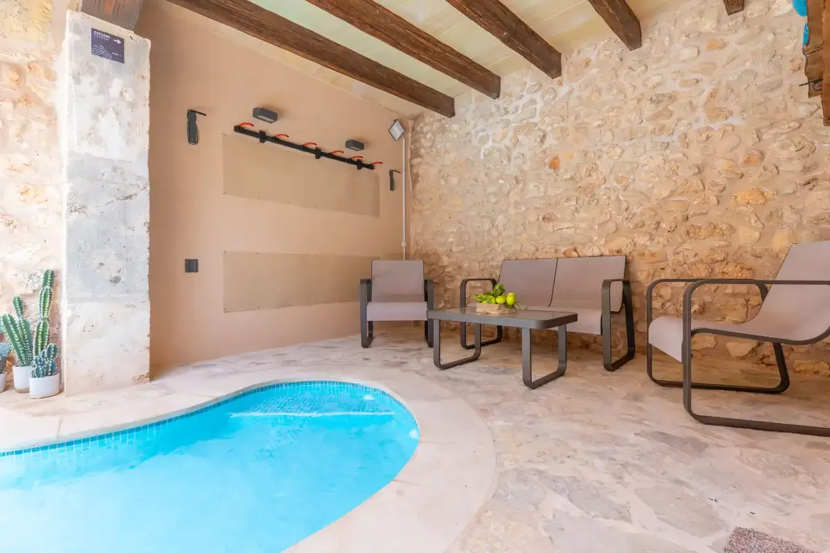 A small indoor pool beside a seating area with exposed wooden ceiling beams.