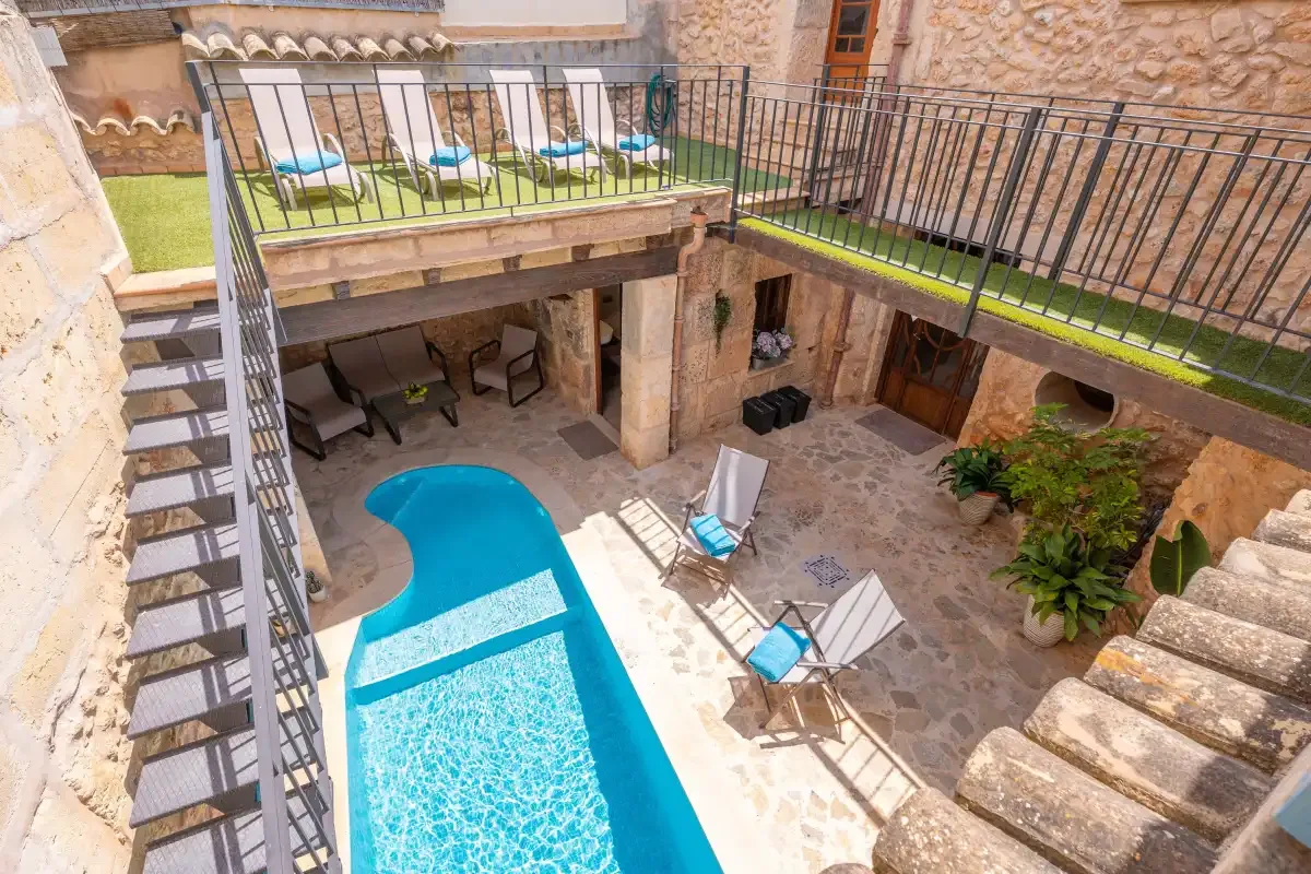 A courtyard pool sits beneath an upper terrace with outdoor seating.