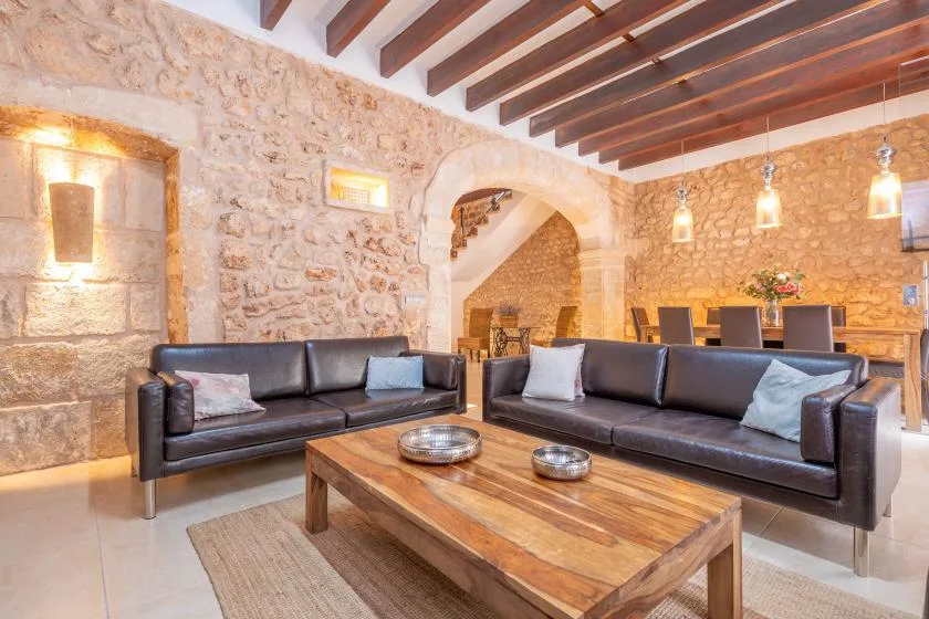 A living room with dark seating and a wooden coffee table in front of a stone wall.