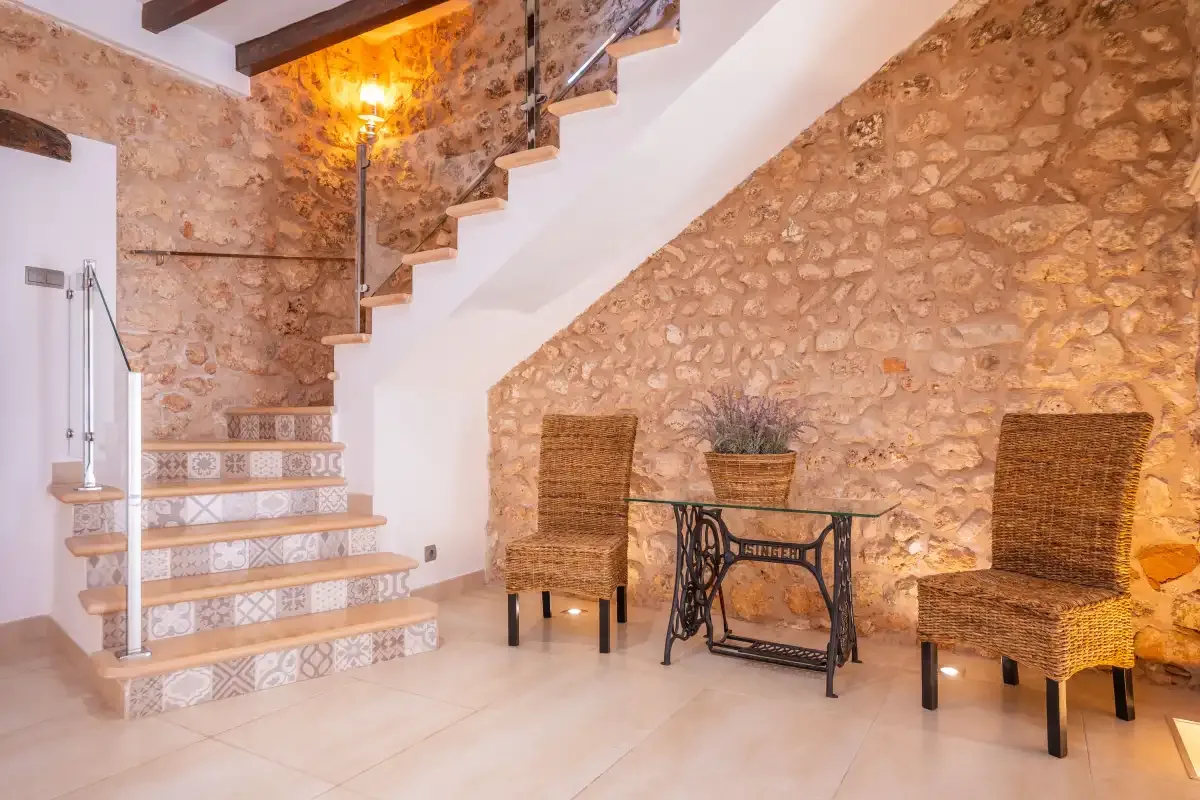 A stone-walled interior with a tiled staircase and a small seating area.