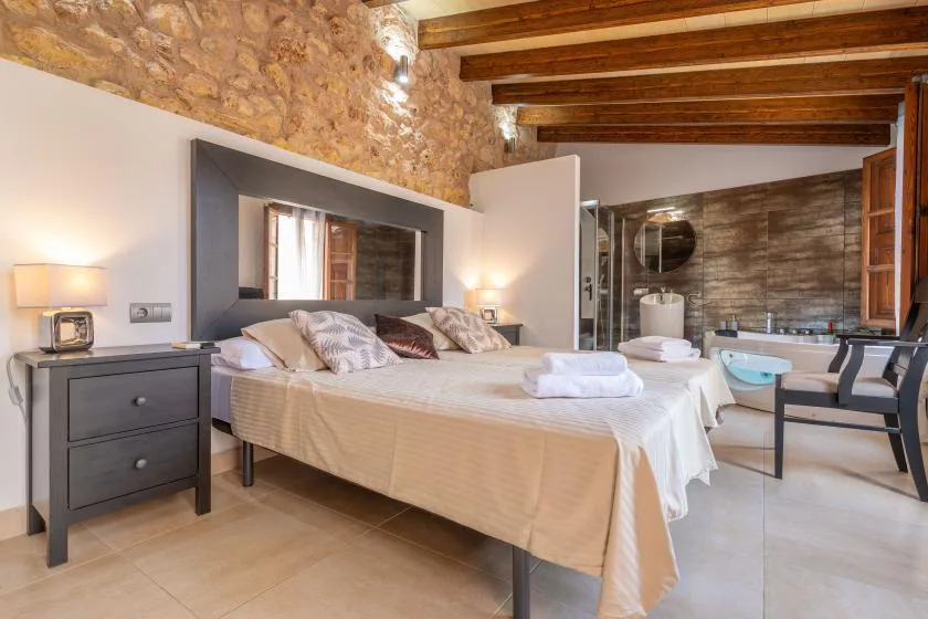 A bedroom with a large bed and an open bathroom area.