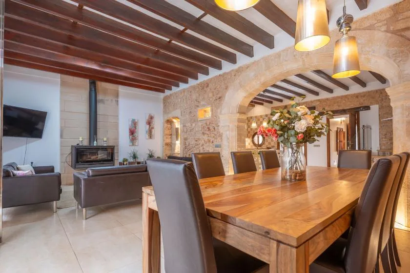A dining area with a long wooden table beneath exposed ceiling beams.