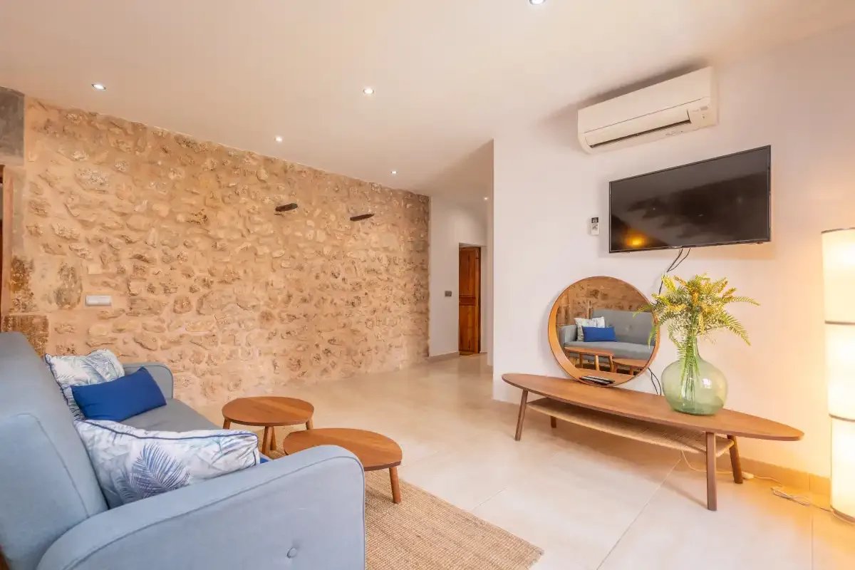 A bright living room with seating, a stone wall, and a television.