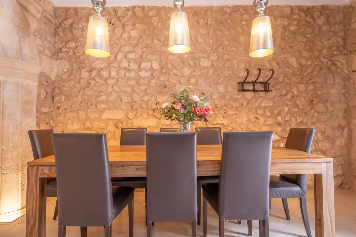 A dining room with a wooden table, seating, and flowers.