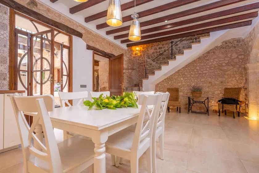 A dining area with a white table and seating beneath exposed ceiling beams.