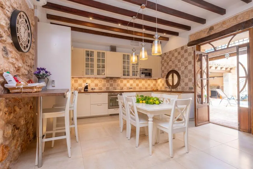 A bright kitchen and dining area with a white table beside open patio doors.