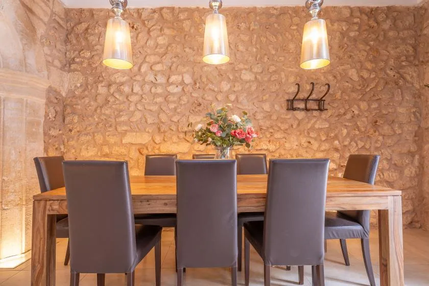 A dining room with a wooden table, dark chairs, and a flower arrangement.