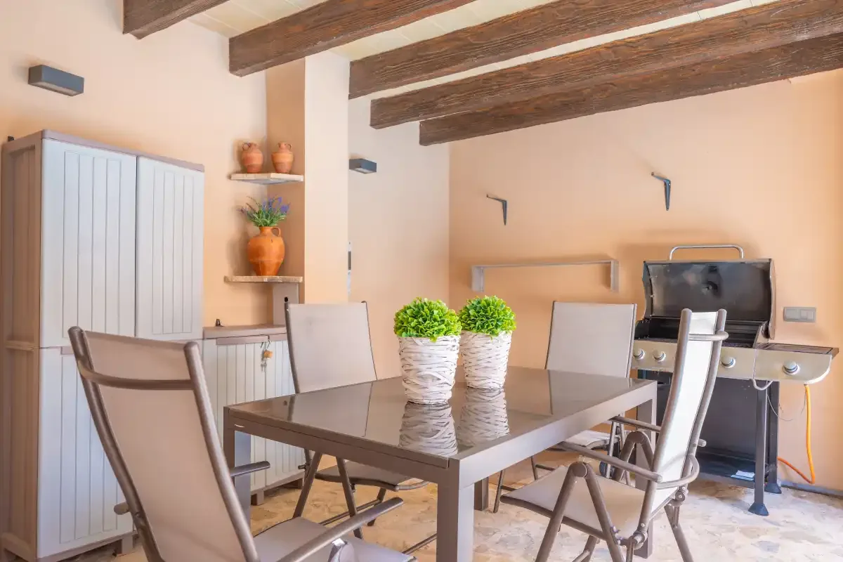 A dining area with a table and chairs beneath exposed wooden ceiling beams.