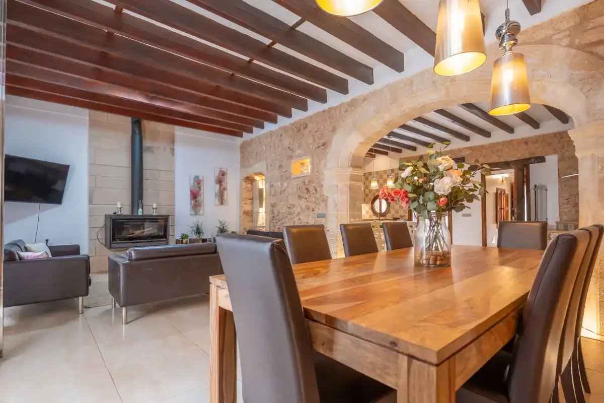 A dining area with a long wooden table beneath exposed ceiling beams.