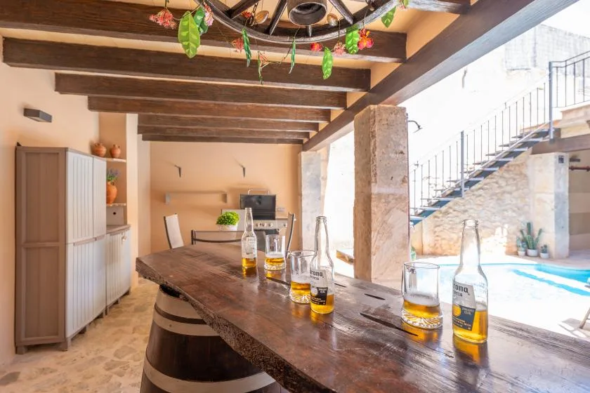 A rustic bar counter overlooks a bright indoor pool beneath exposed wooden beams.