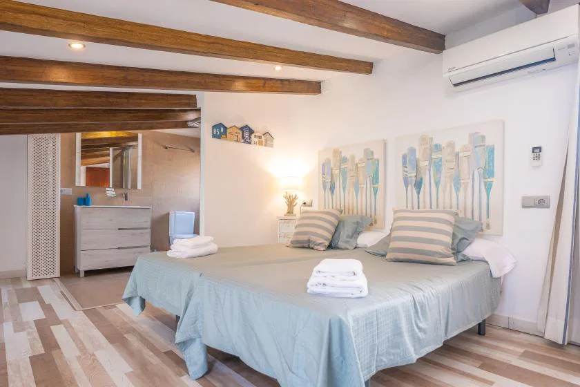 A bedroom with a bed dressed in pale blue bedding and abstract wall art.