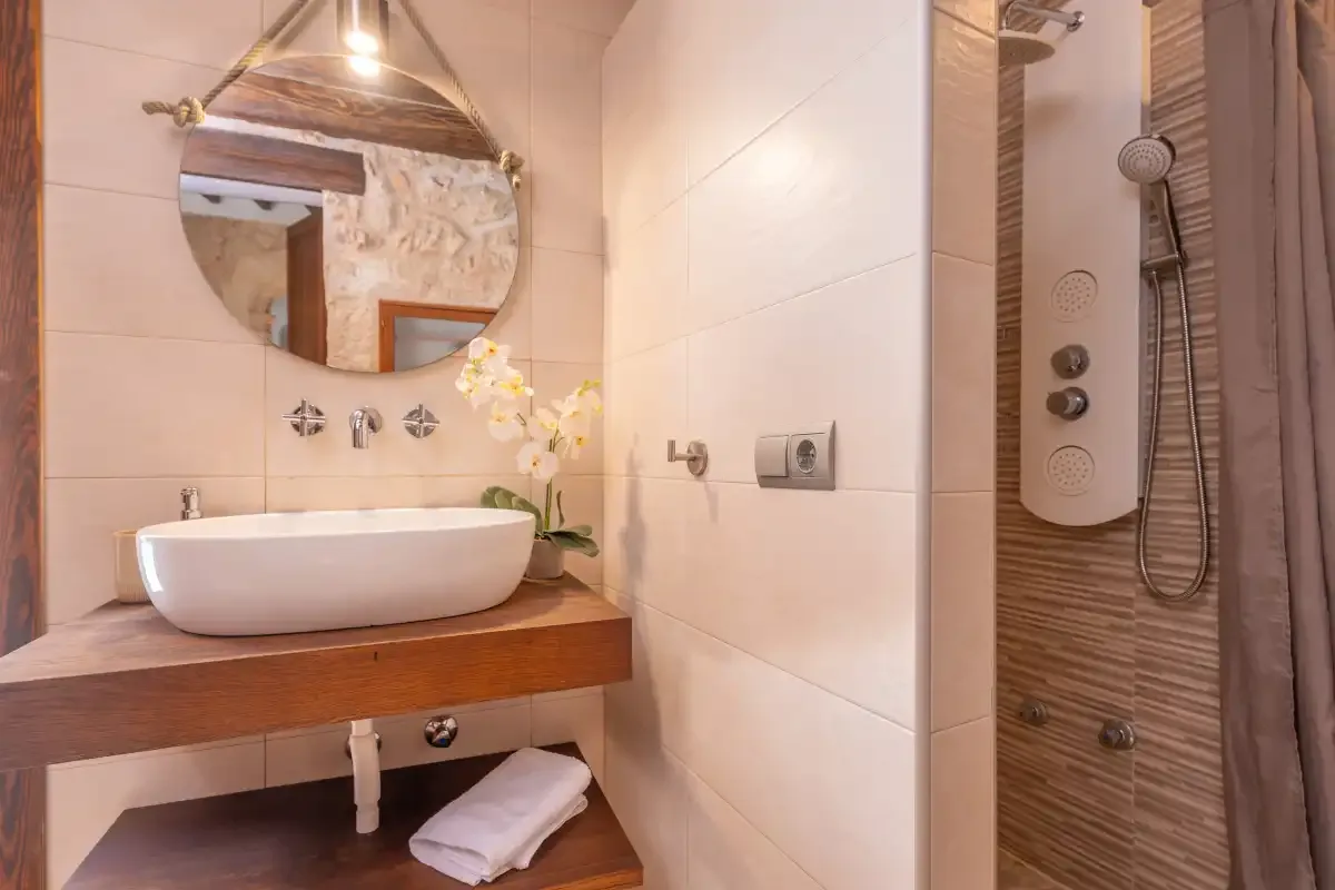 A bathroom vanity with a vessel sink stands beside a tiled shower.